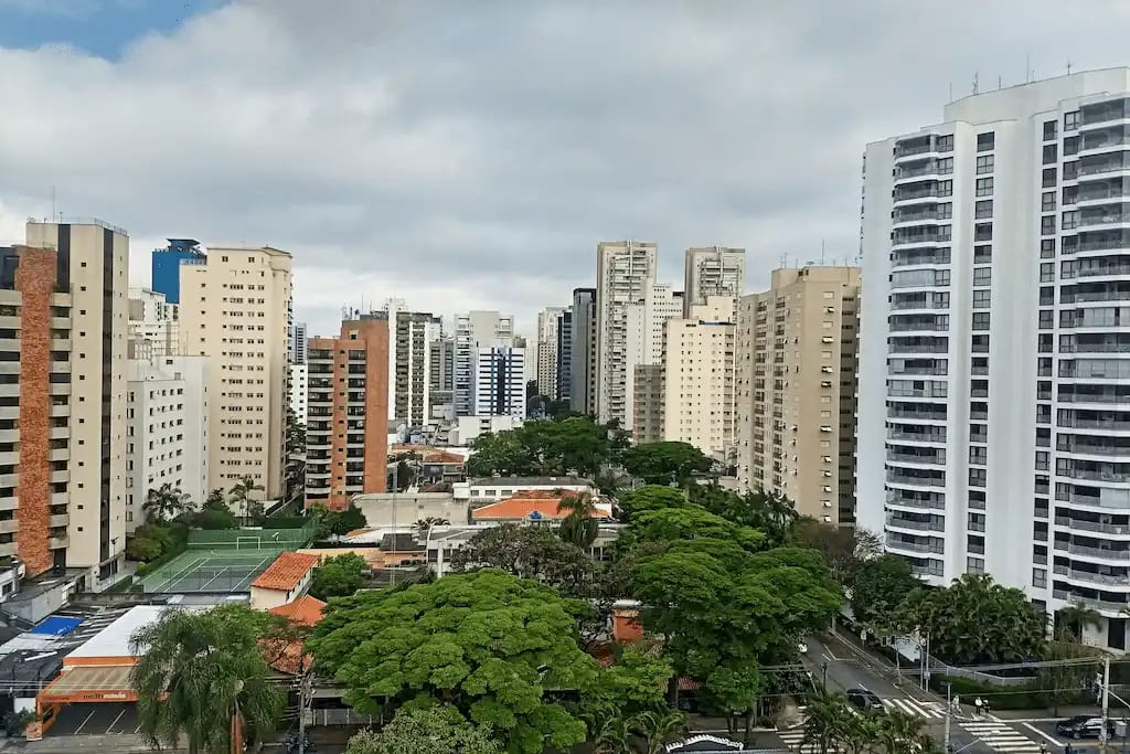 Vista aérea do bairro de Moema em São Paulo, com prédios residenciais altos, ruas arborizadas e quadra esportiva entre as construções.