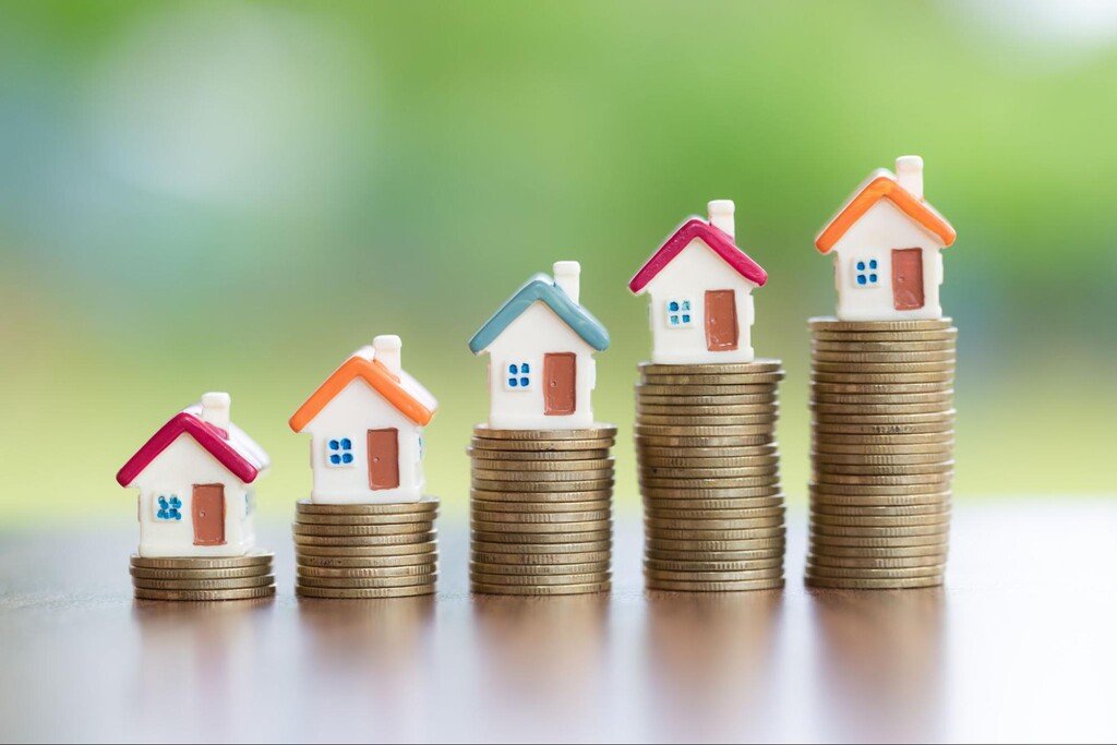 moedas empilhadas com casinhas em miniatura, representando o investimento em apartamentos na planta