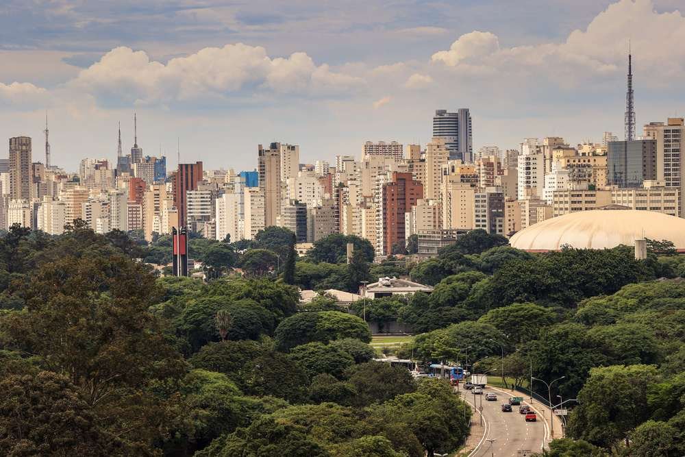 Vista panorâmica do skyline de São Paulo com arranha-céus e parques, destacando a mistura de natureza e urbanização na cidade.
